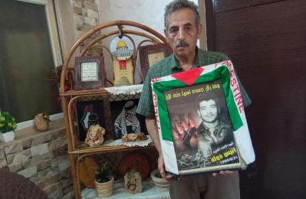 حسن دولة يحمل صورة شقيقه الأسير الشهيد أنيس المحتجز جثمانه منذ استشهاده في السجن الإسرائيلي عام 1980. (الجزيرة)