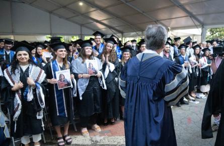 Image of Arab Studies Georgetown graduating class with Keffiyes and holding posters of Shireen Abu Akleh while Blinken walks by