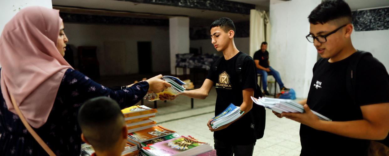 Schoolboys collect unedited textbooks as part of a protest by Palestinian parents of what they say is Israeli censorship of school textbooks in Shuafat refugee camp in Jerusalem October 1, 2022. REUTERS/Ammar Awad