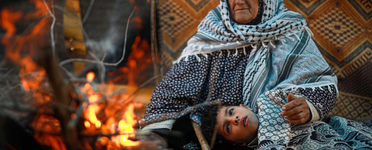 A Palestinian mother warms her children during the cold weather at the Beit Lahia area in the northern Gaza Strip. Majority World CIC / Alamy Stock Photo. 27 December 2022.